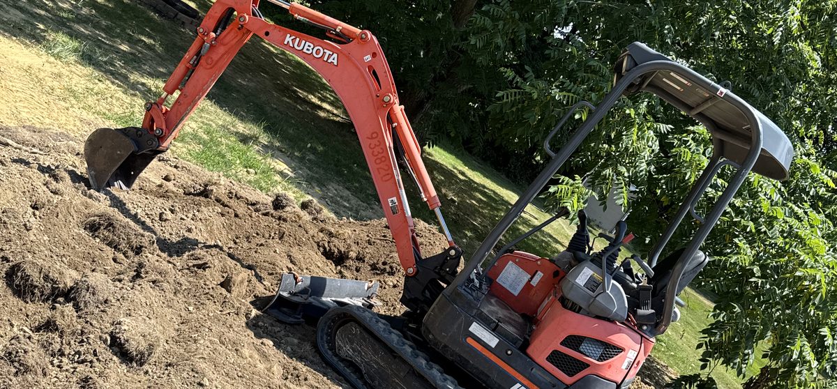 Mini excavator grading a sloped residential yard